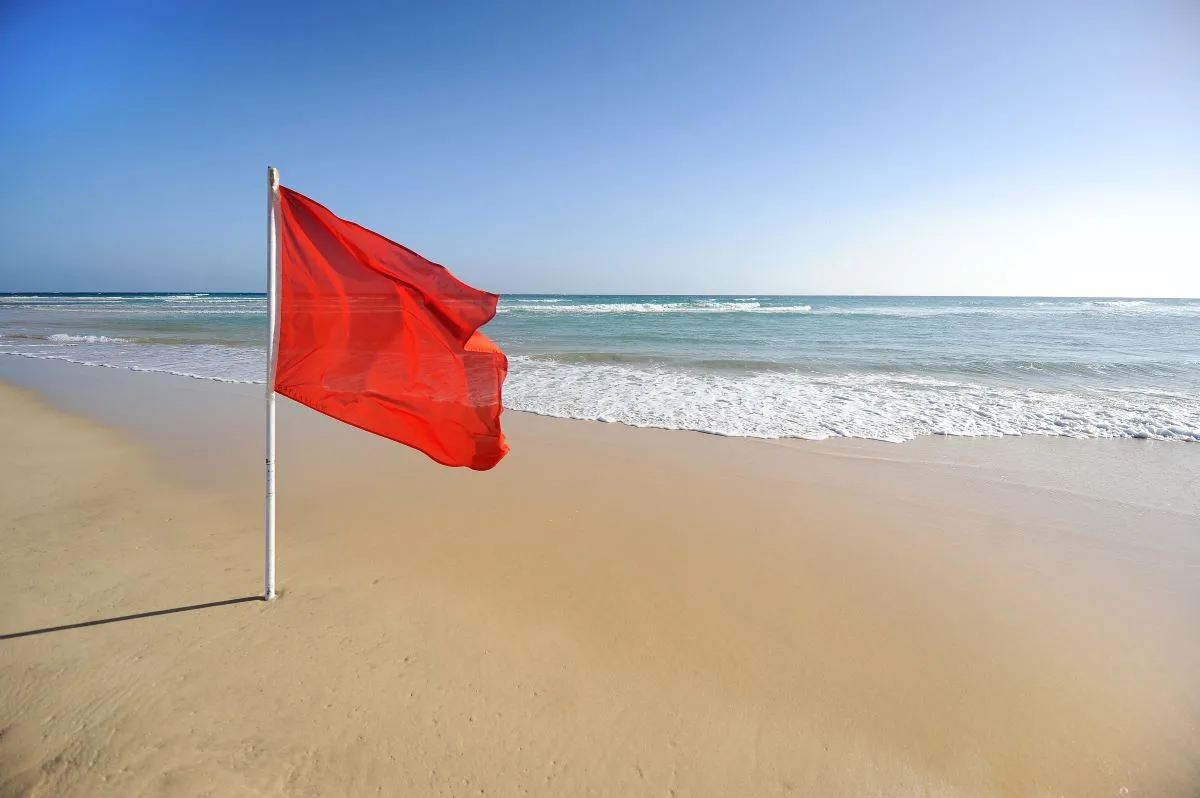 Warning sign red flag beautiful beach with blue sky turquoise sea jpg